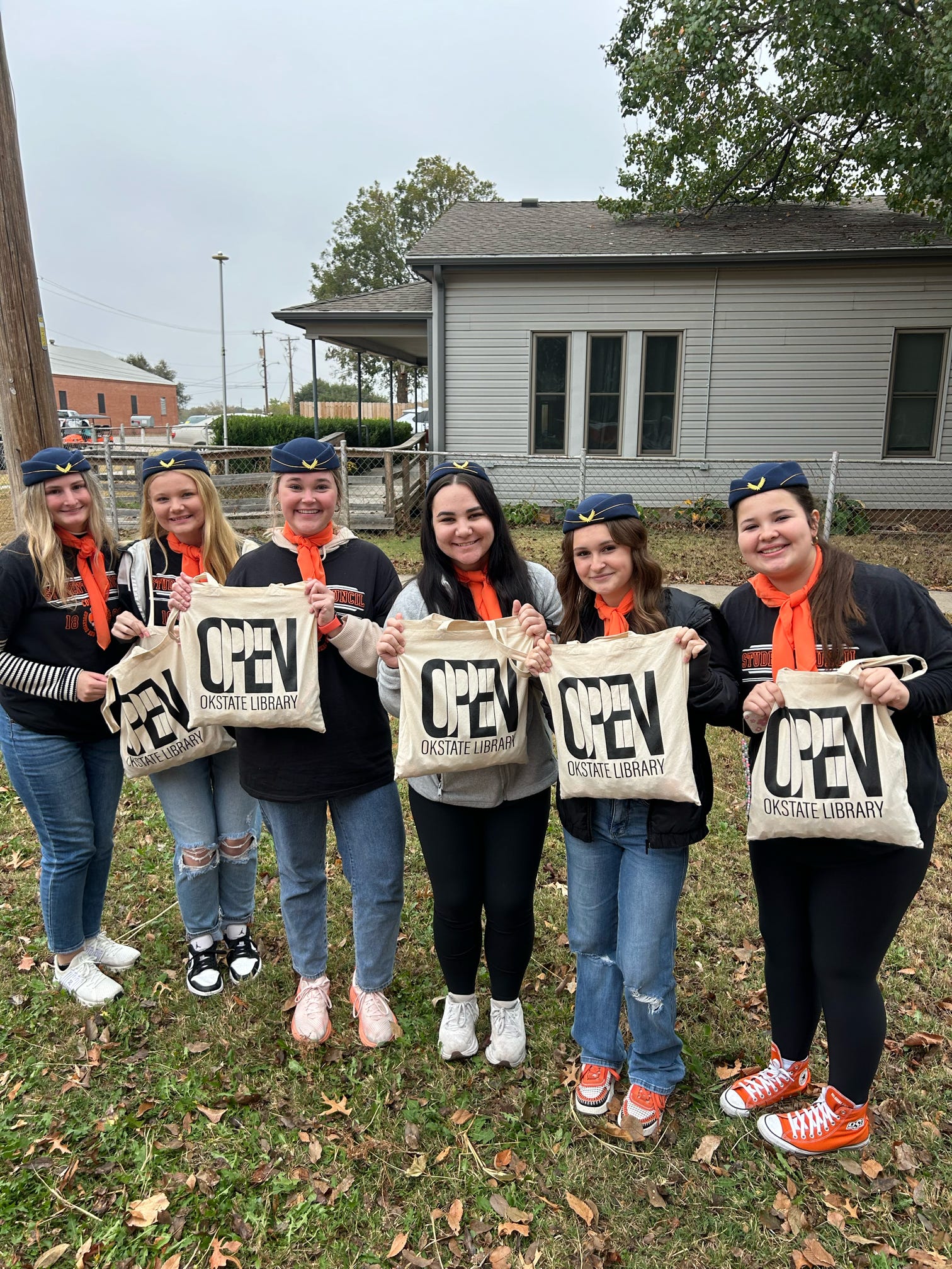 Members holding up OPEN Okstate library tote bags