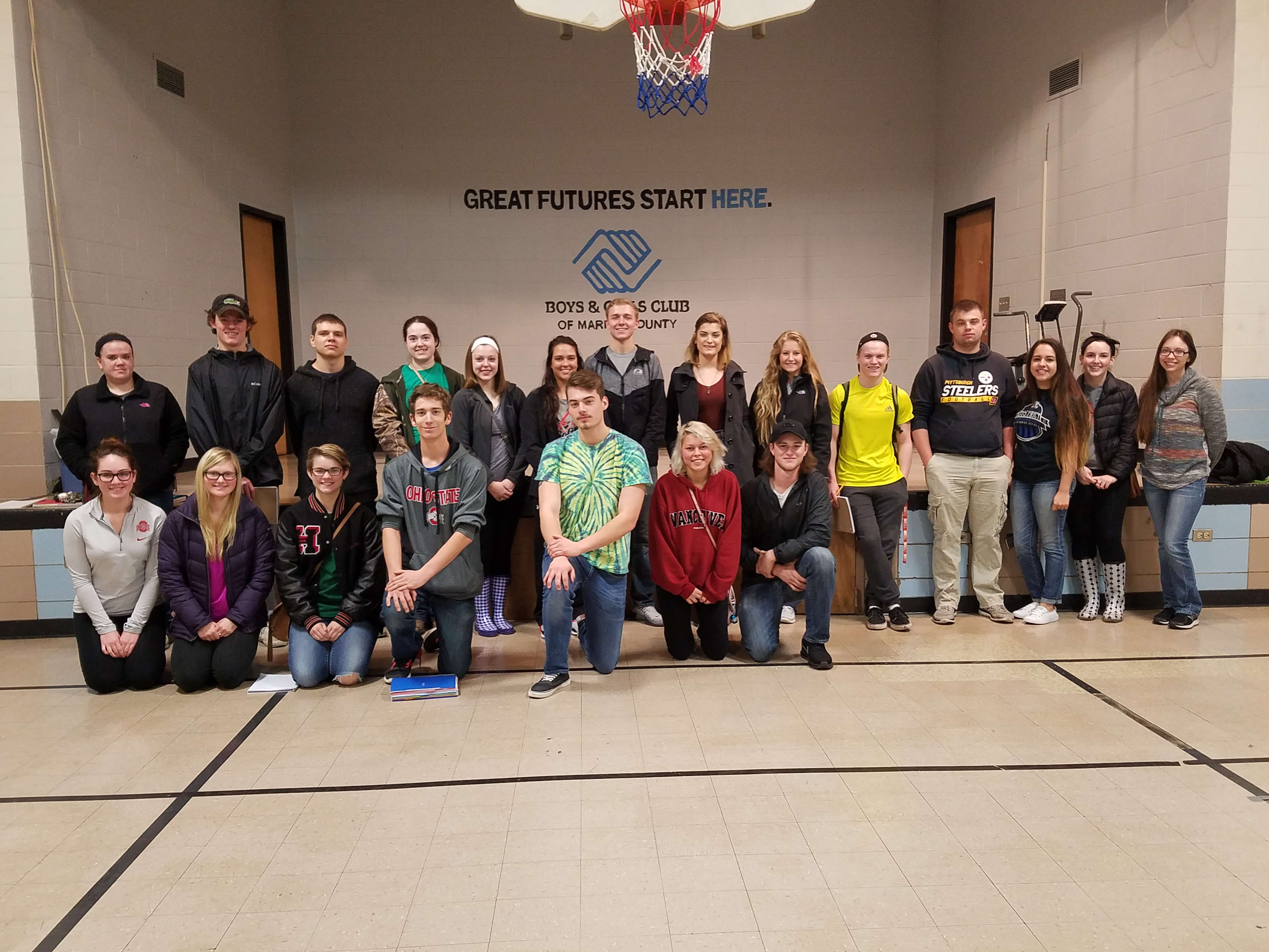 A group of students pose before a company logo