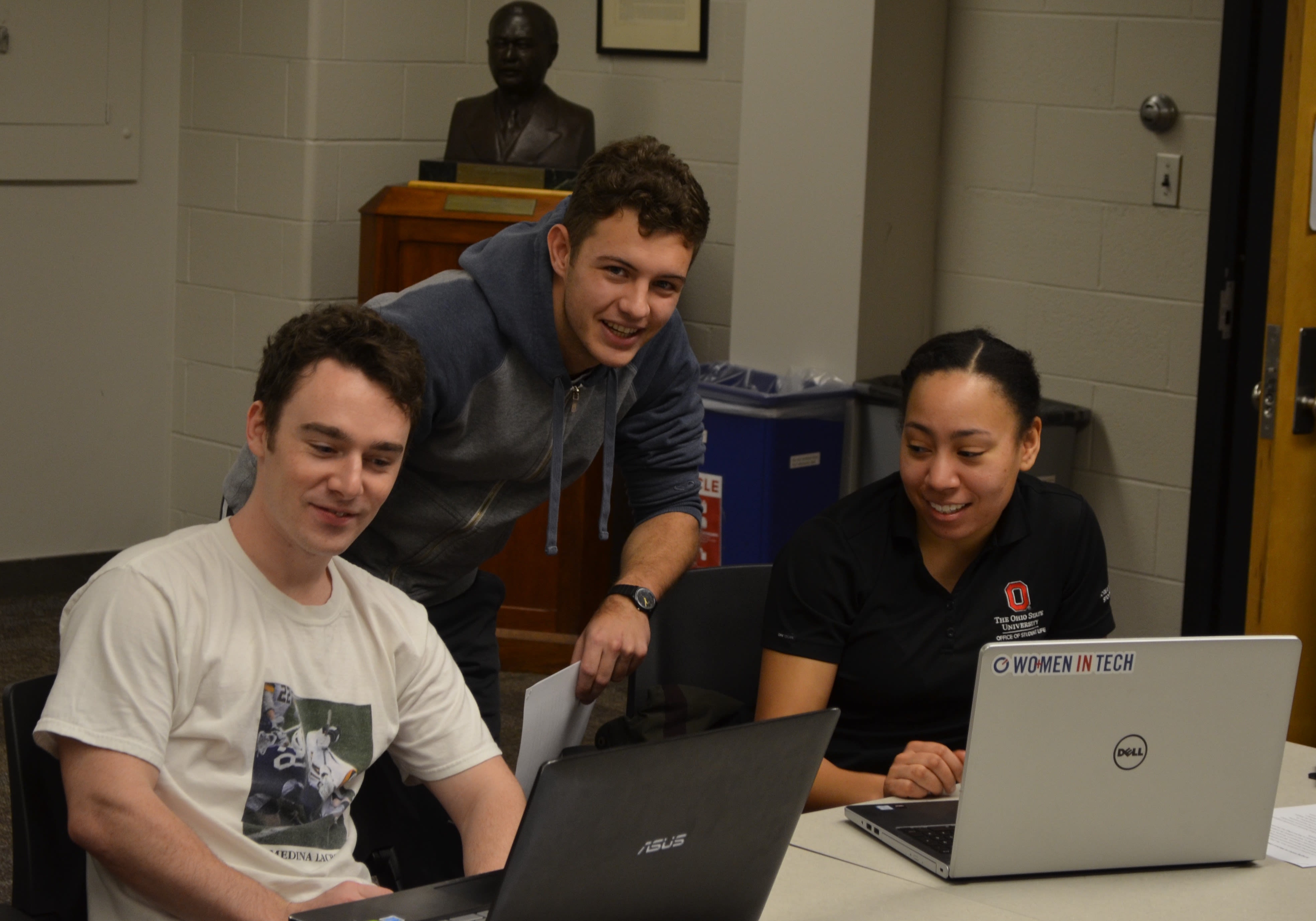 Three individuals working around laptops
