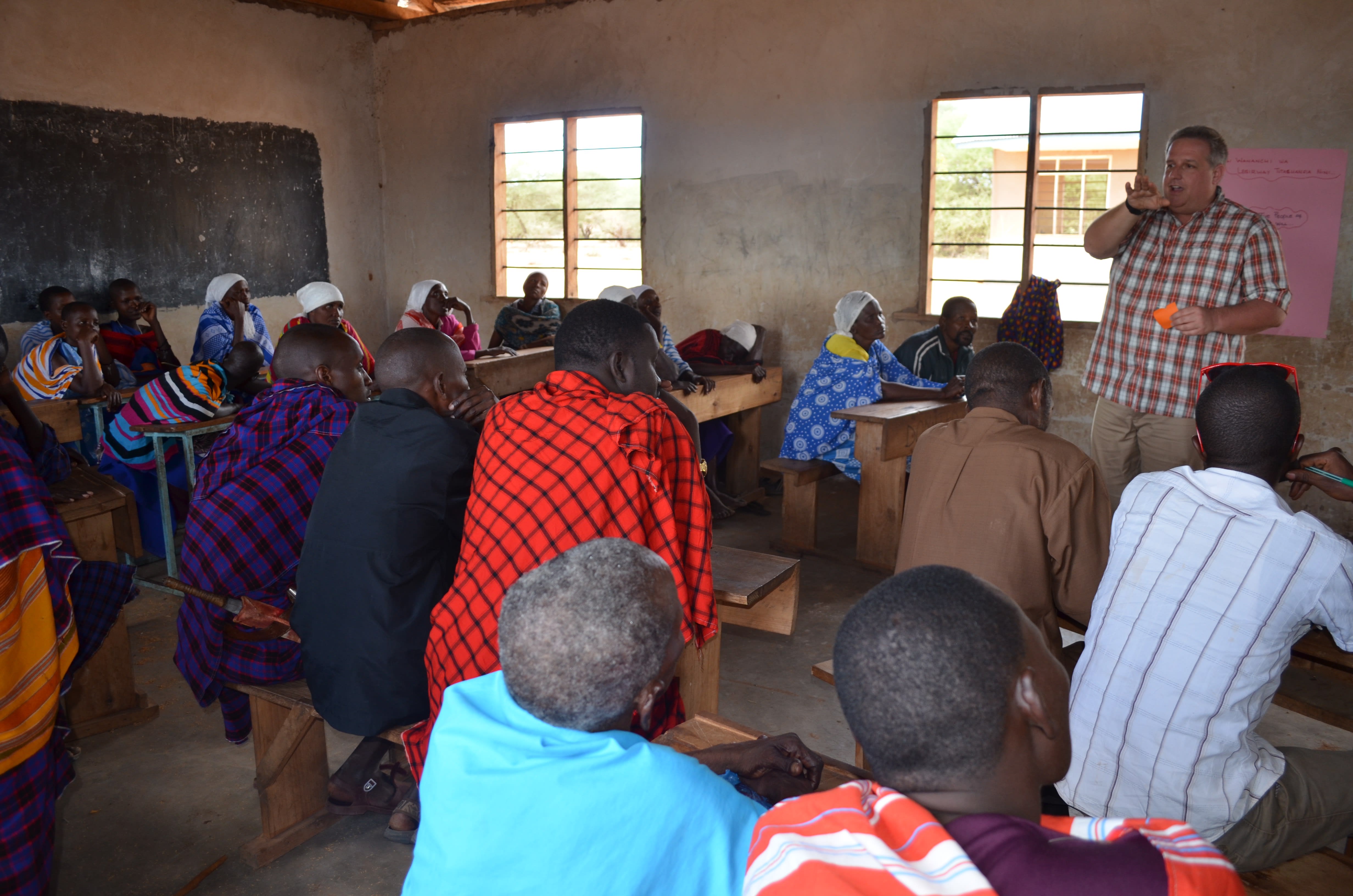 A man talks to Marwa adults in concrete classroom