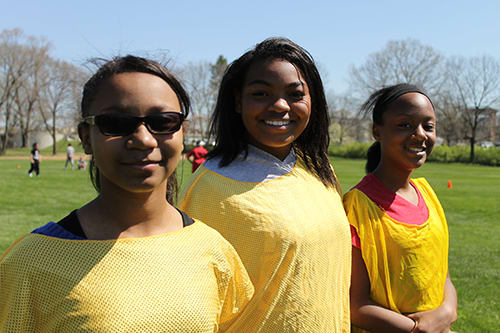 Three girls wearing yellow smile to the camera