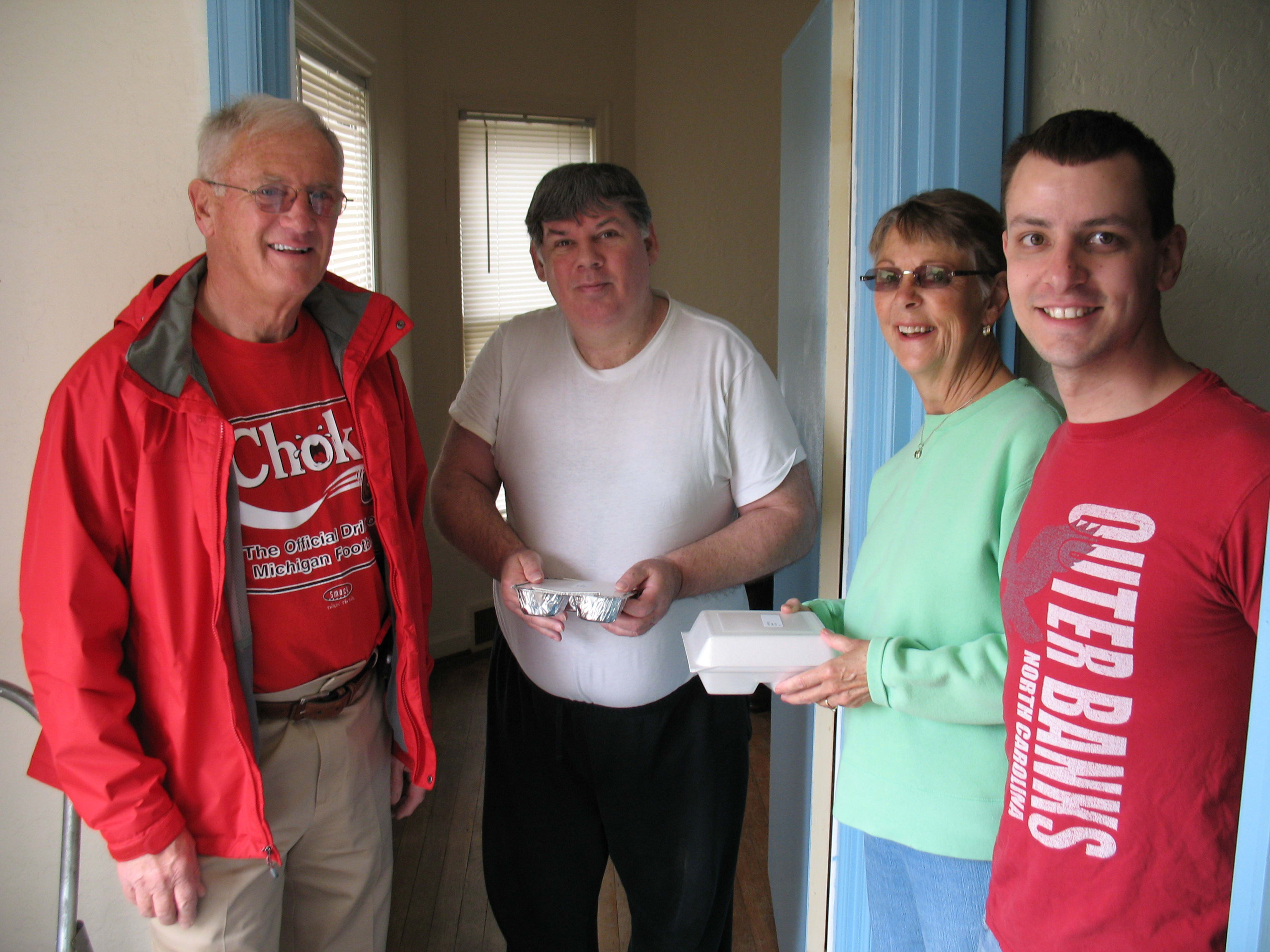 People gathered by front door with food in hand