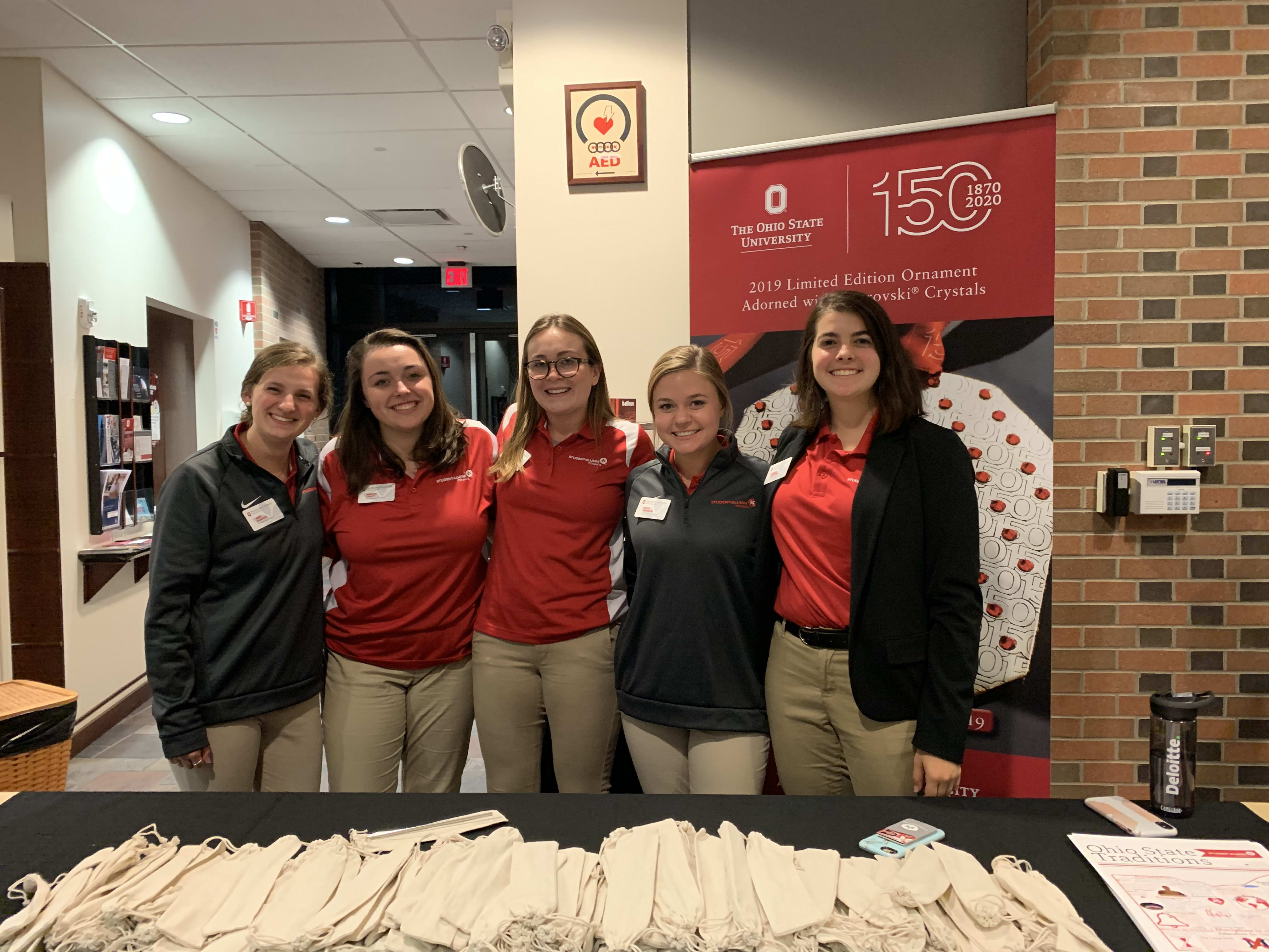 5 volunteers manning a table with small bags