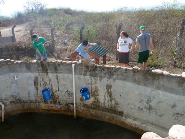 Four students work together at a large well