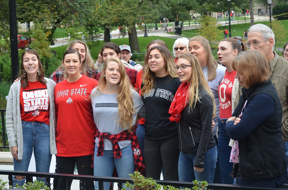 A crowd of students huddled together by the lake