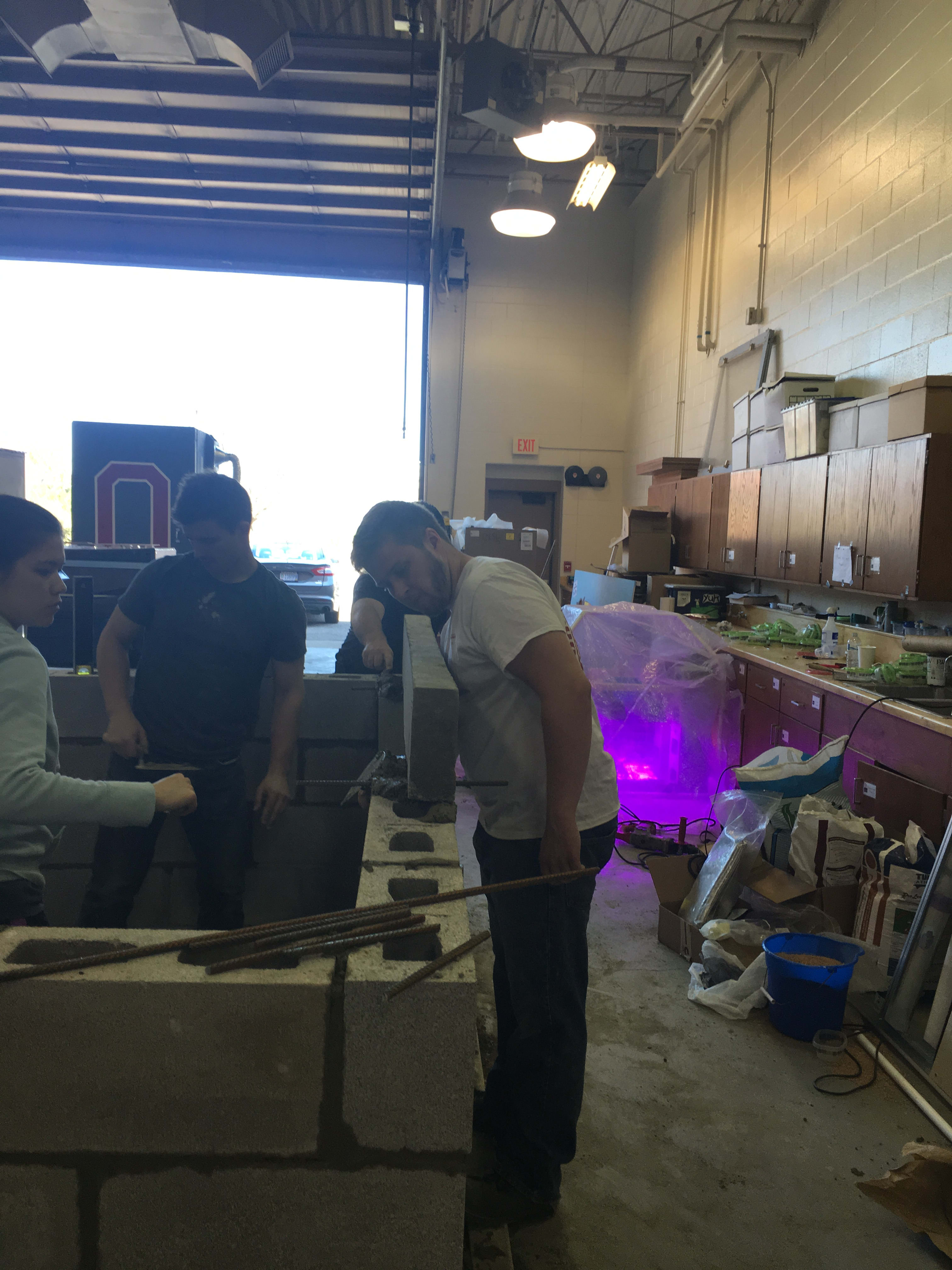 Volunteers practicing brick laying in a warehouse