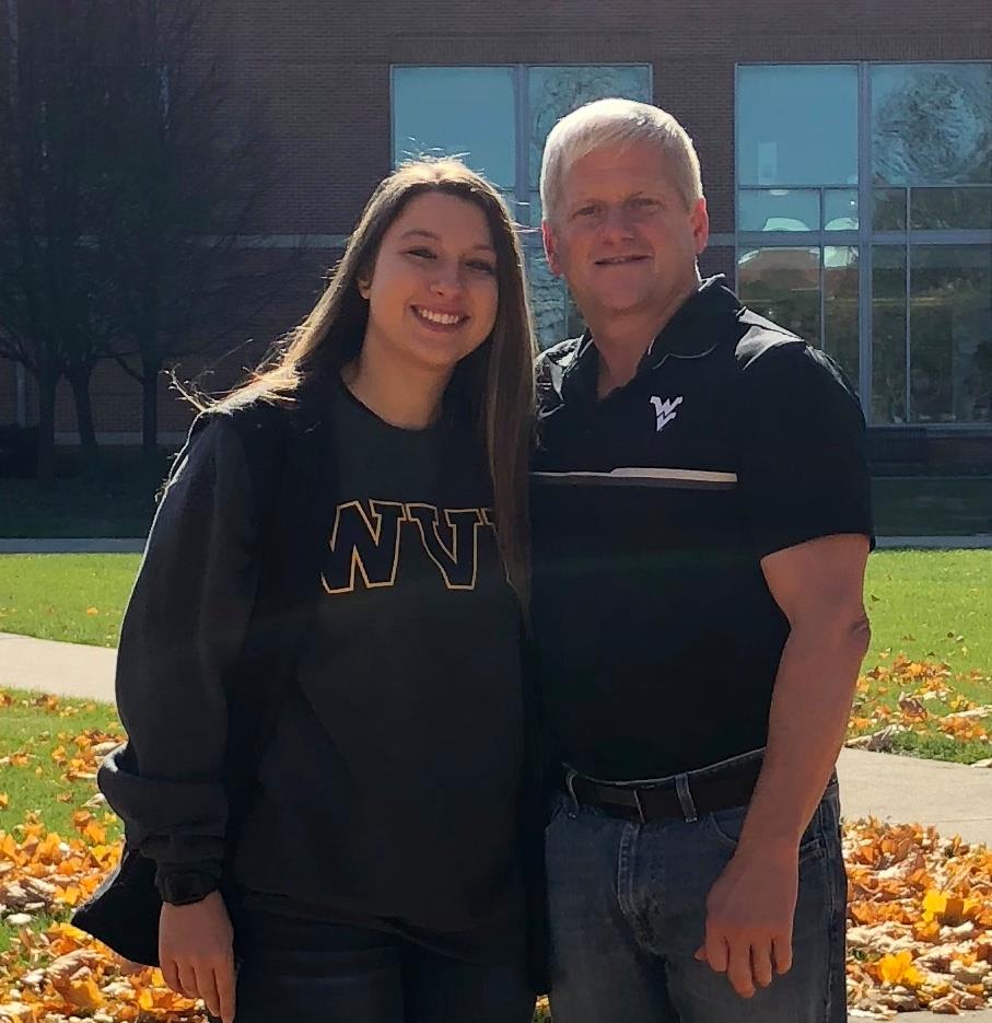 A student and her father standing before building