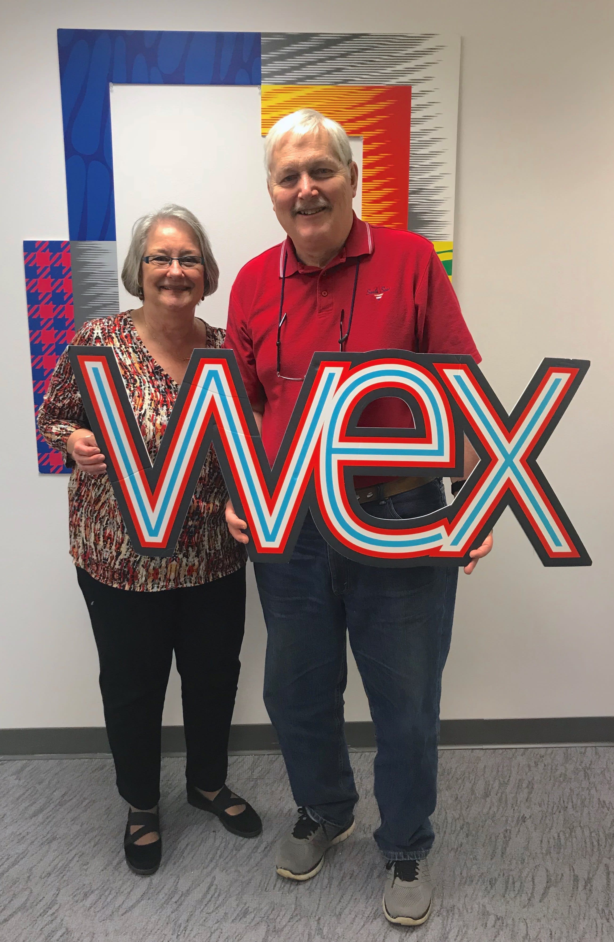 Two individuals side by side, holding 'WEX' cutout