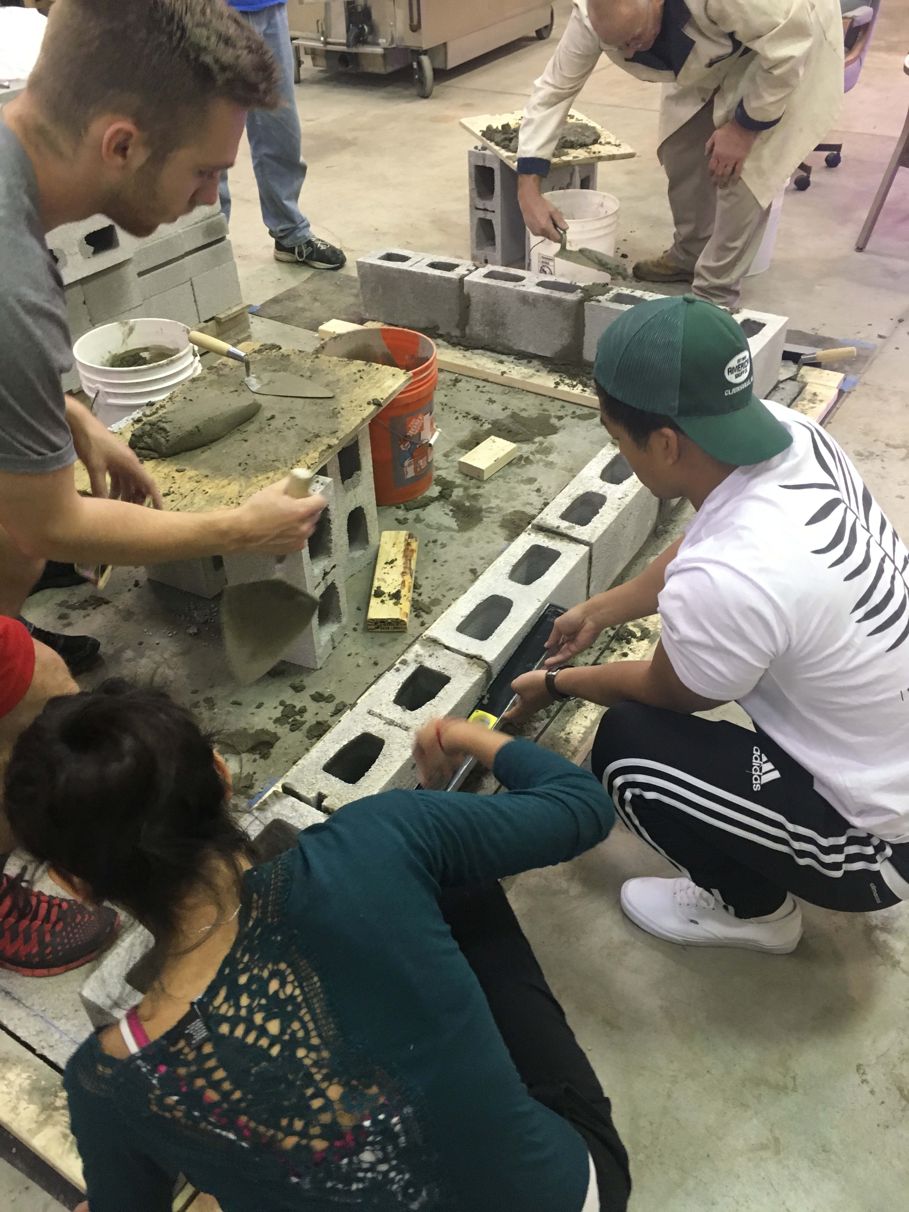 Volunteers laying the bricks at the house's base