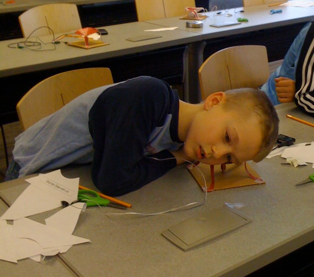 A boy leans over a table to view his project