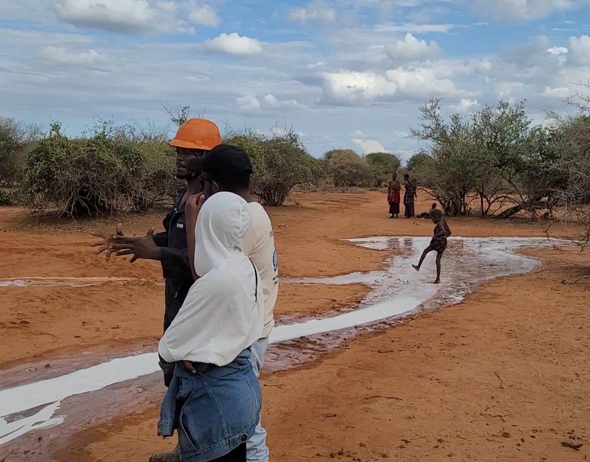 While volunteers speak, a child plays in water
