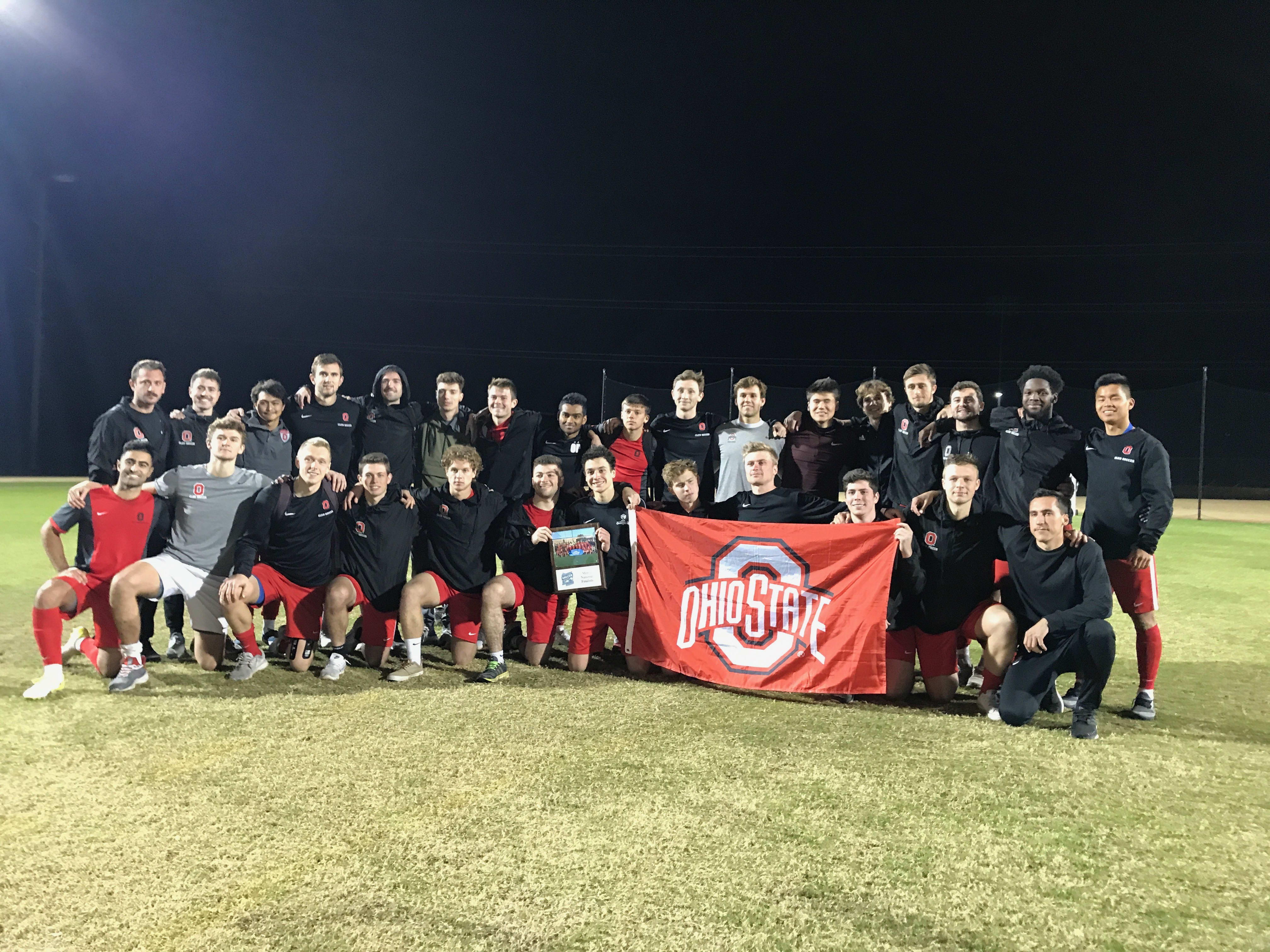 The Club team holding a flag and a plaque