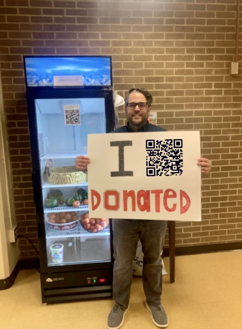 A man standing by a fridge with a 'I Donated' sign