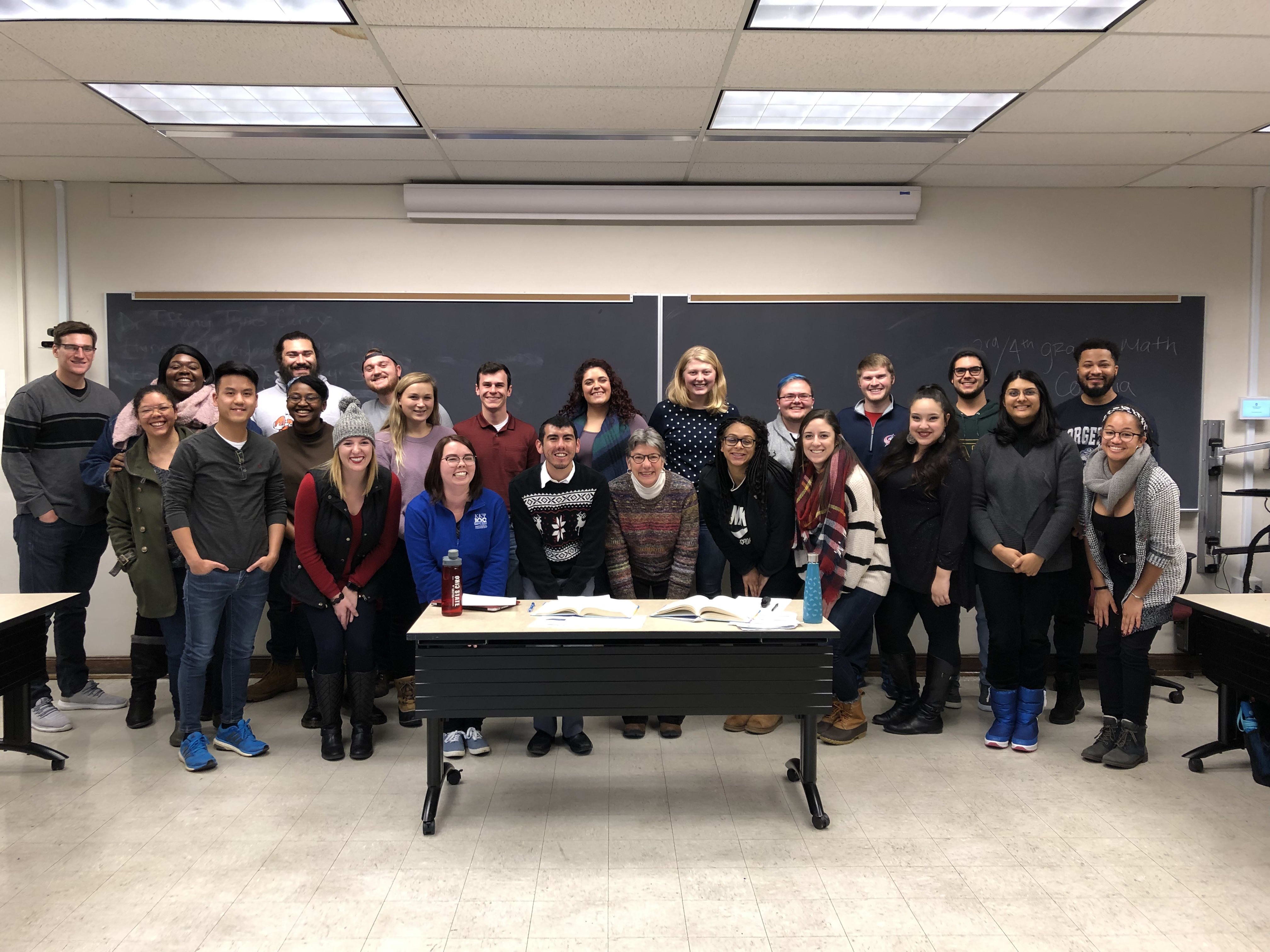 A large group before a blank chalkboard