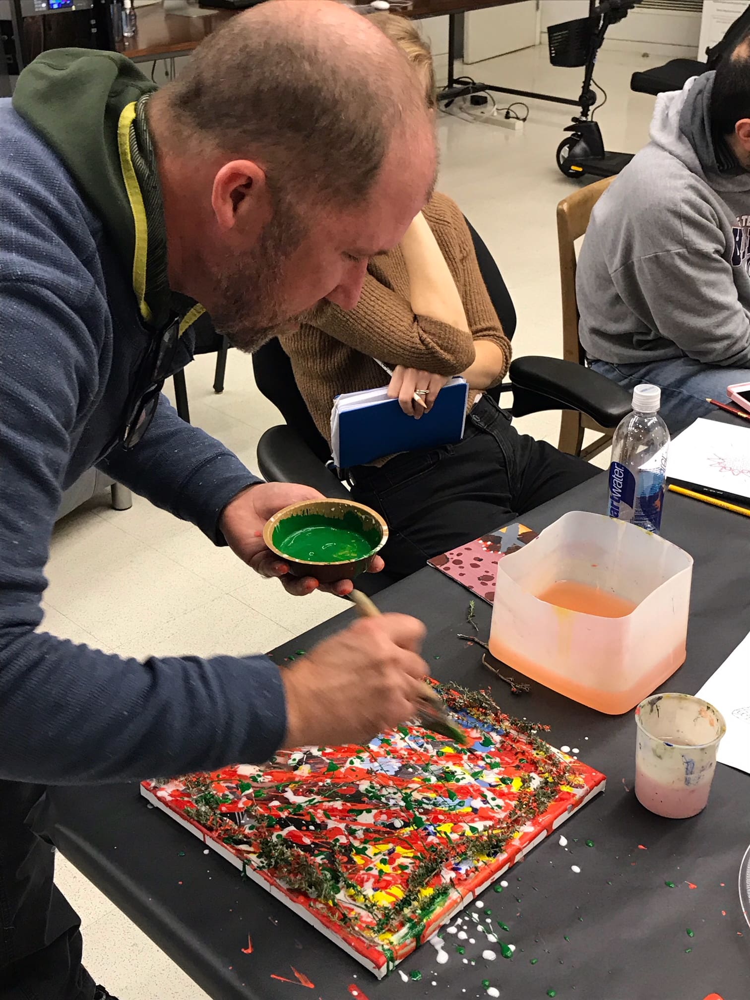 A man paints on a flat canva with a green paint