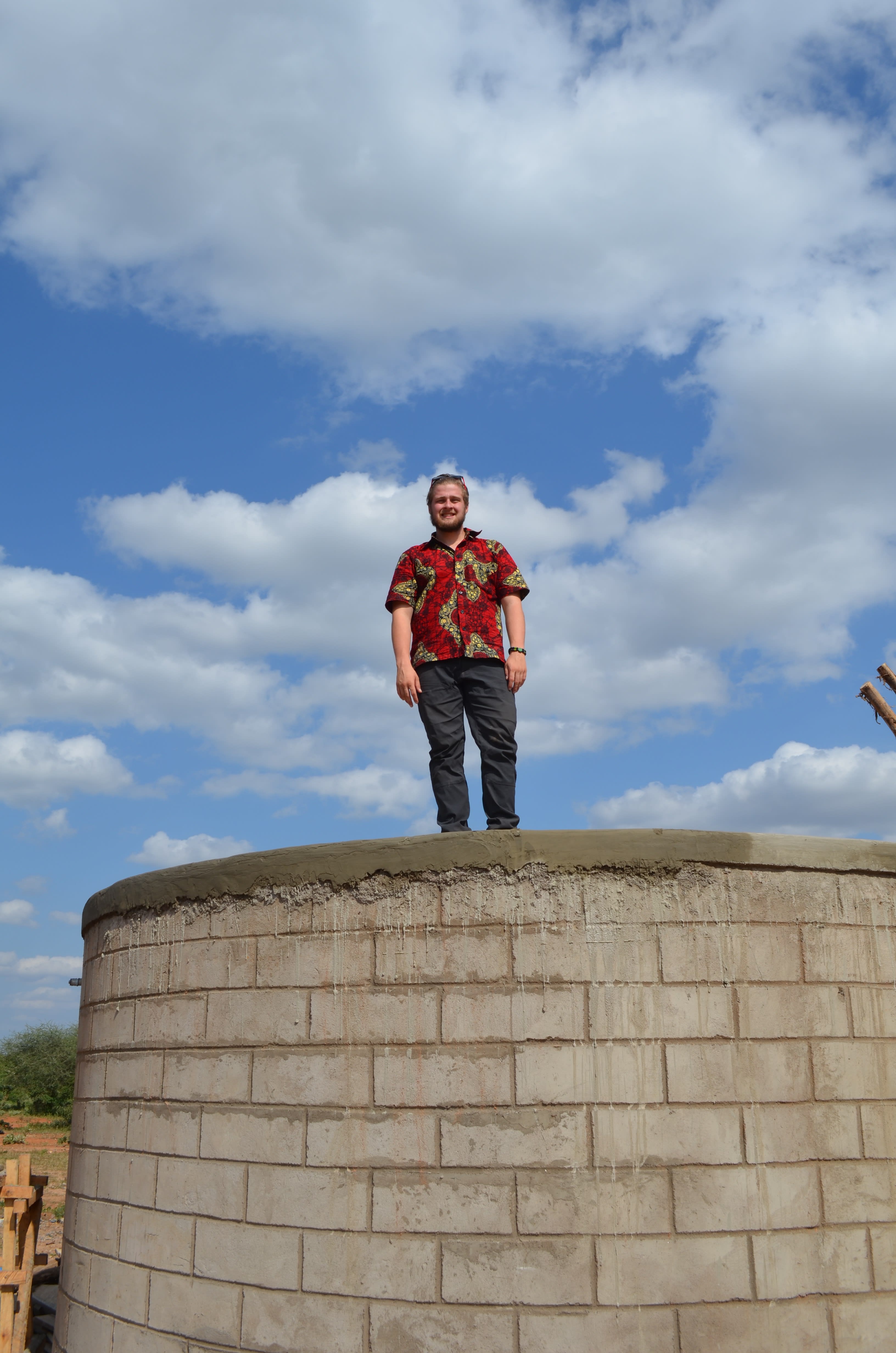 A man stands on top of a large, concrete wall