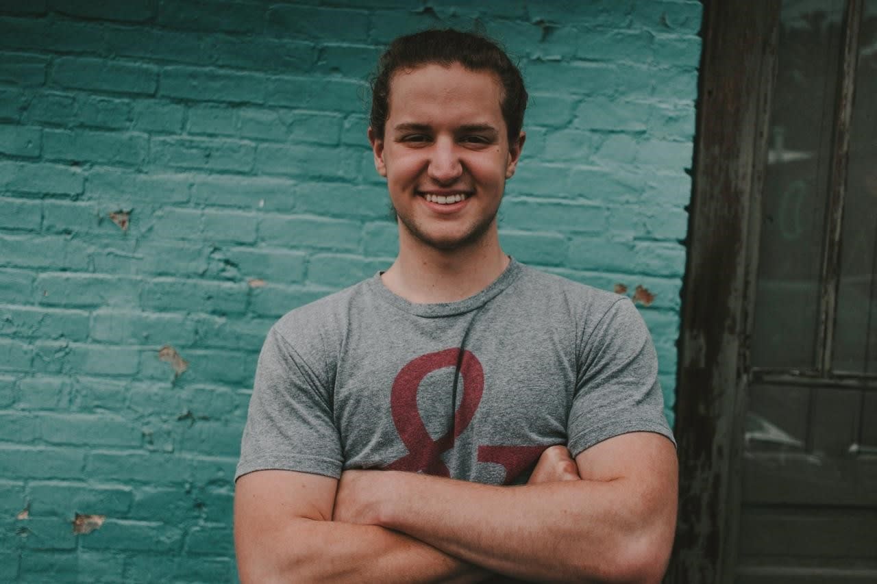 An OSU student before a teal, brick wall