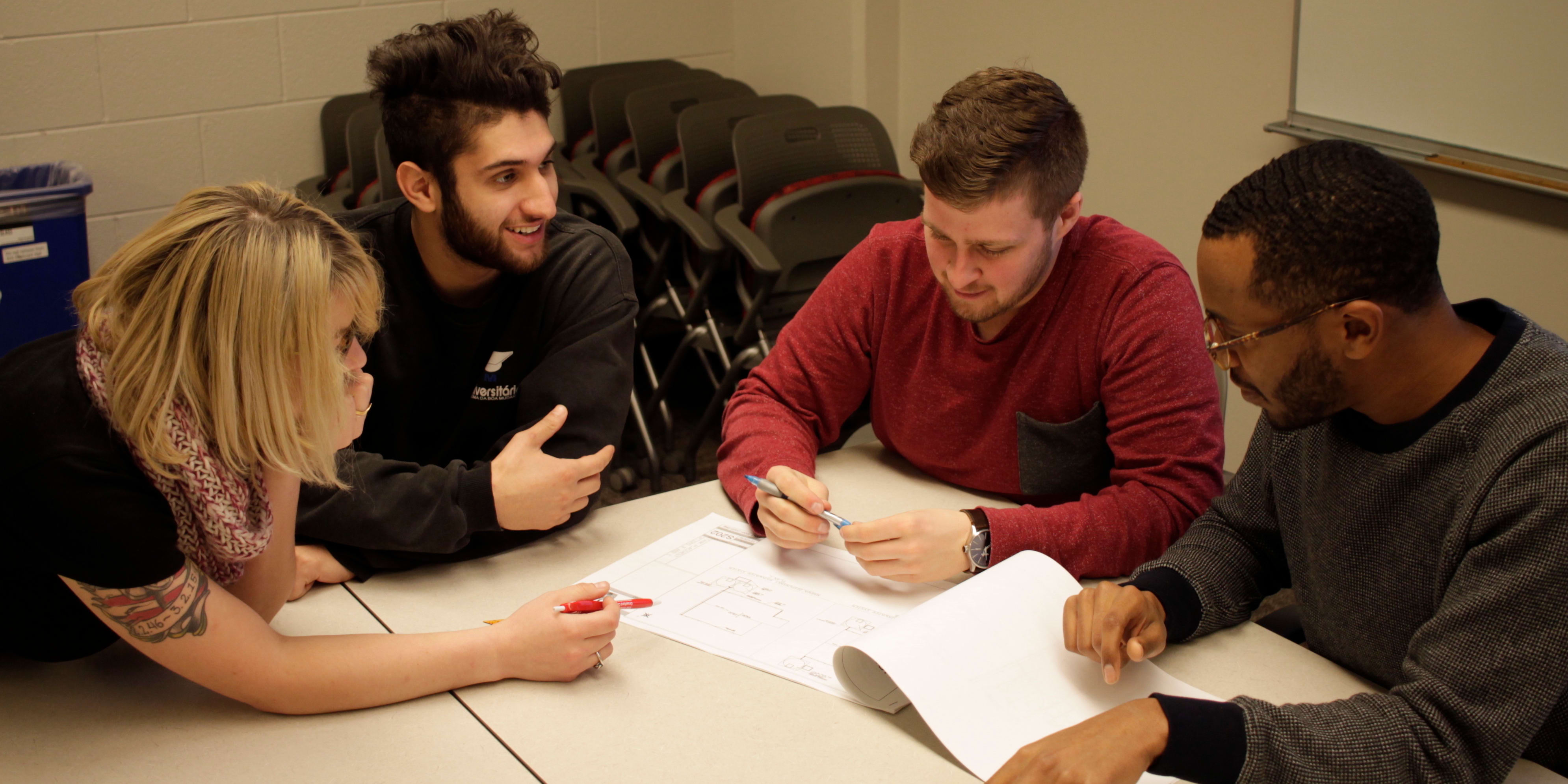 Four individuals work together on a paper