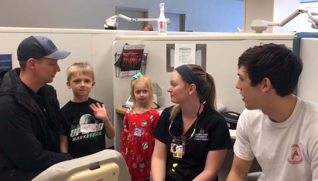 Three adults and two children stand inside office