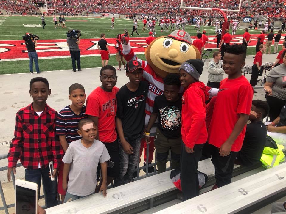 A group of children huddled around Brutus Buckeye