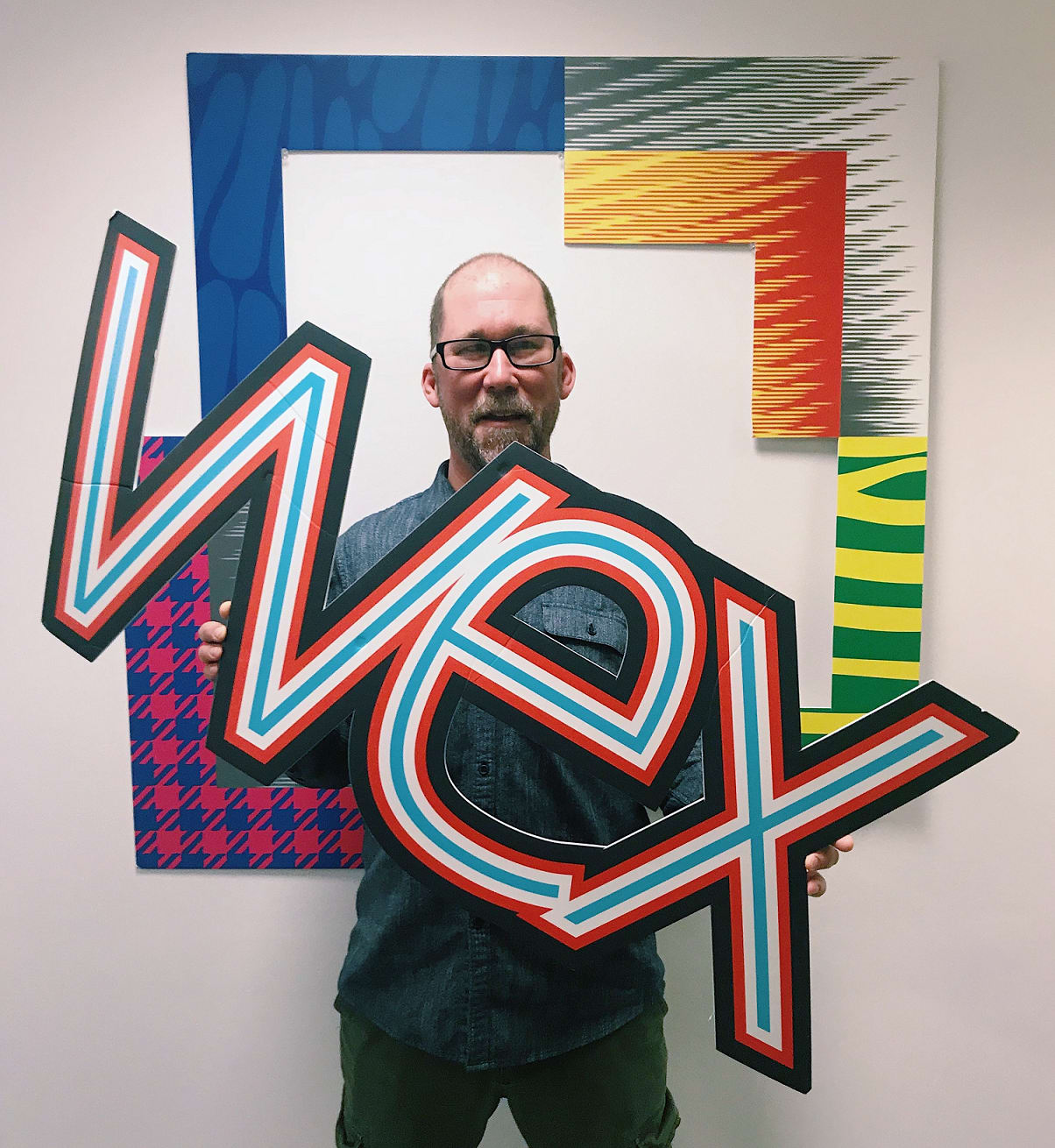 A man holds a 'WEX' cutout