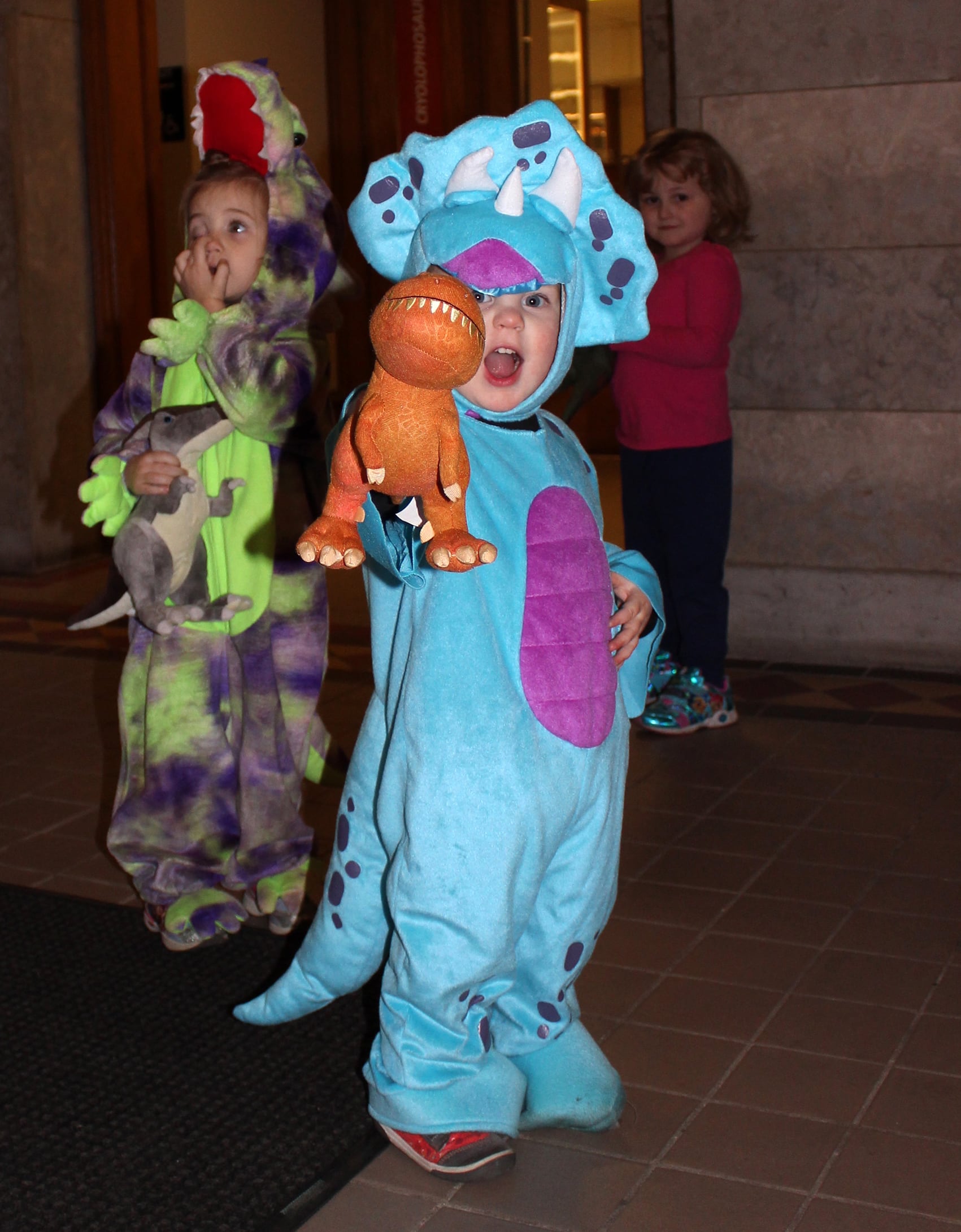 Young children dressed in dinosaur onesies