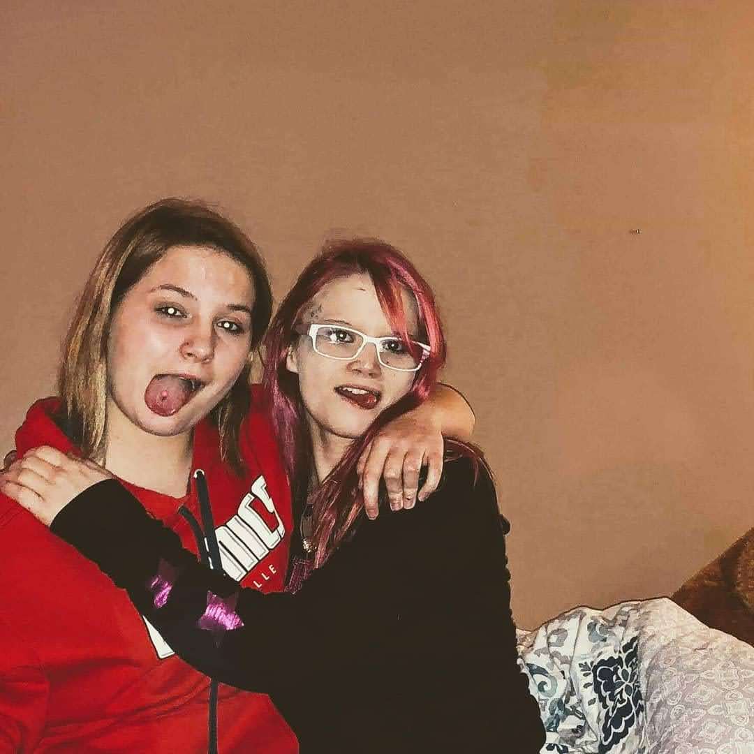 Two young women side hugging one another