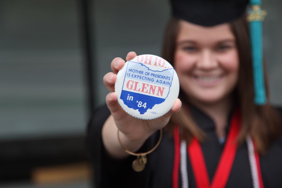 A graduate holding a Glenn Ohio pin