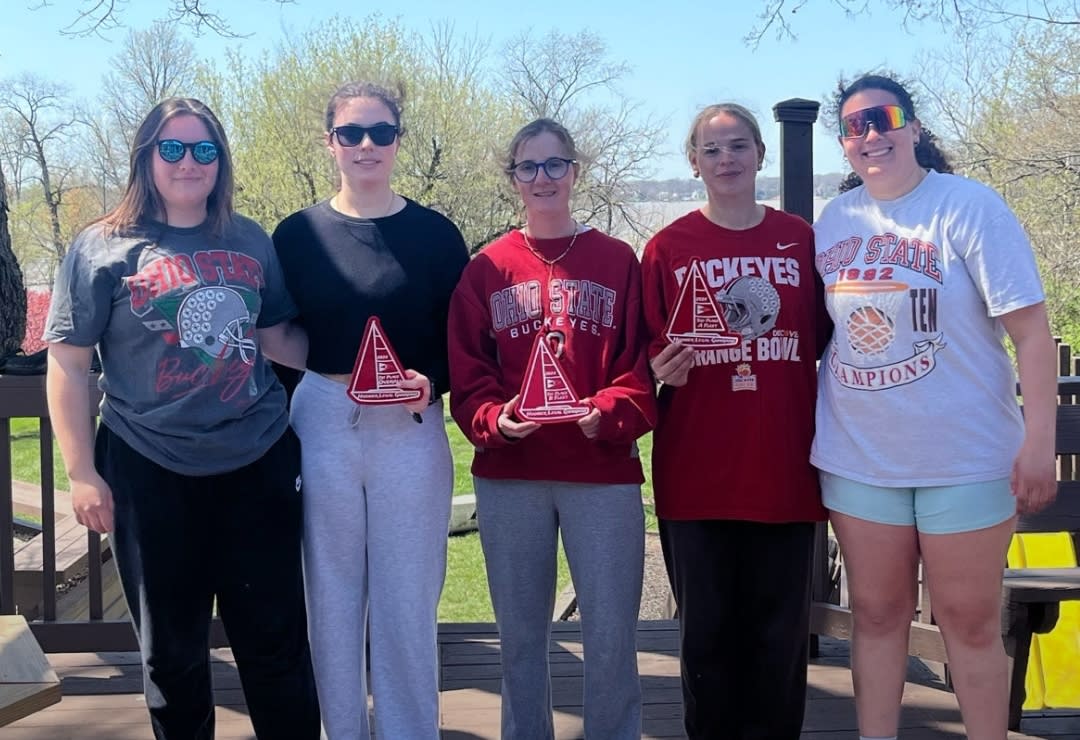 Five club members holding paper sail boats
