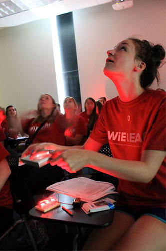An older student lights up her classroom's ceiling