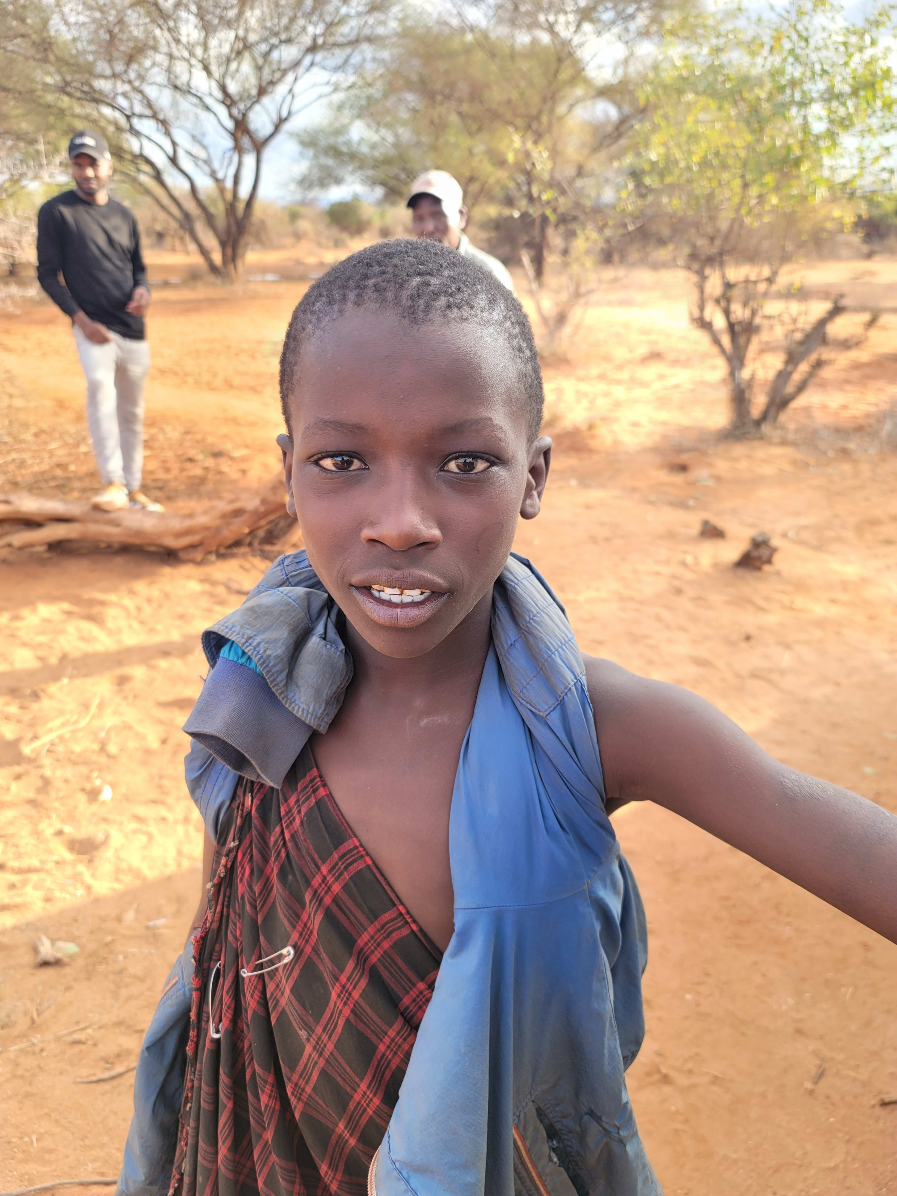 A young individual stands on sandy land