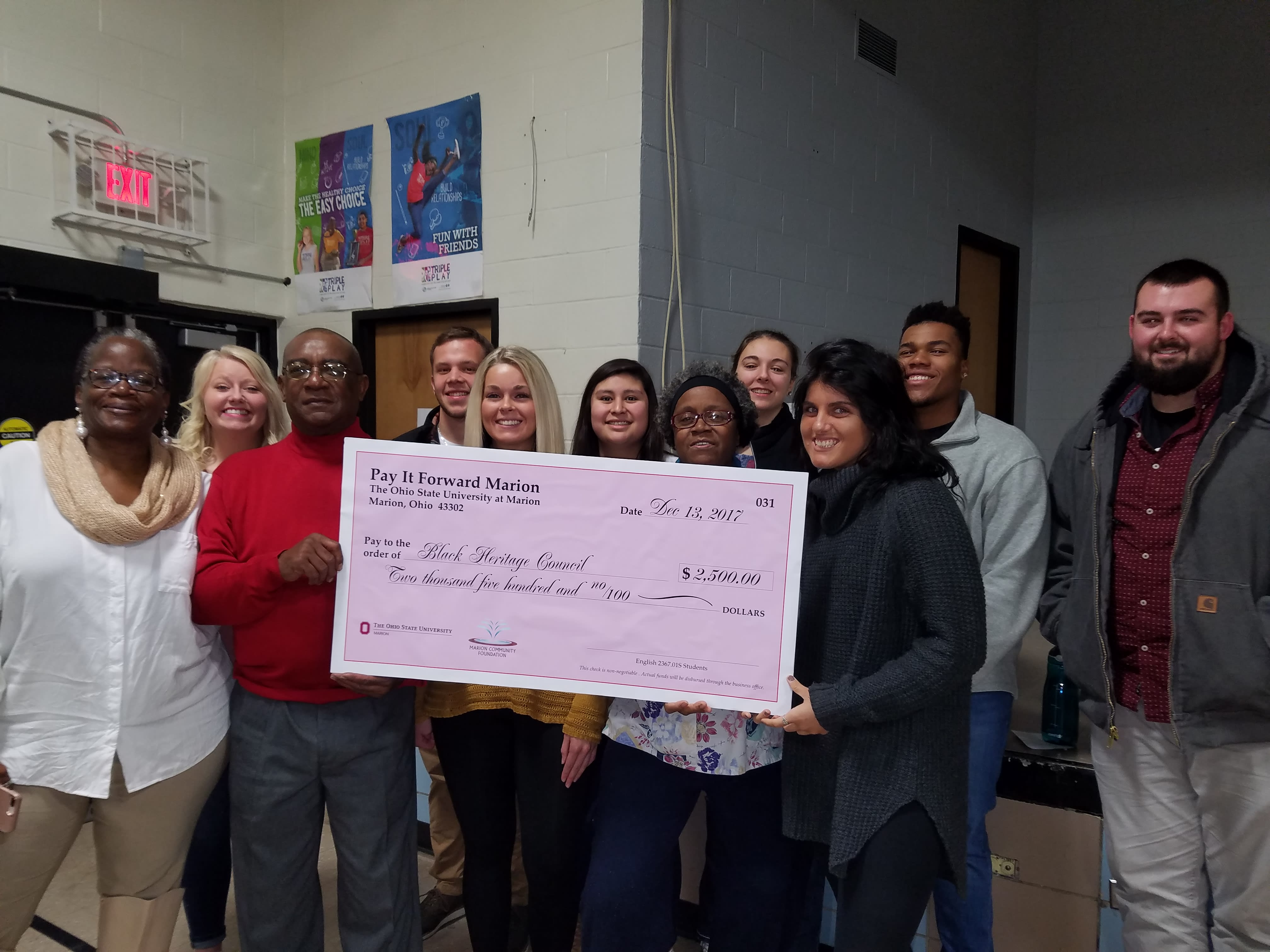 Individuals hold the Pay it Forward Marion check