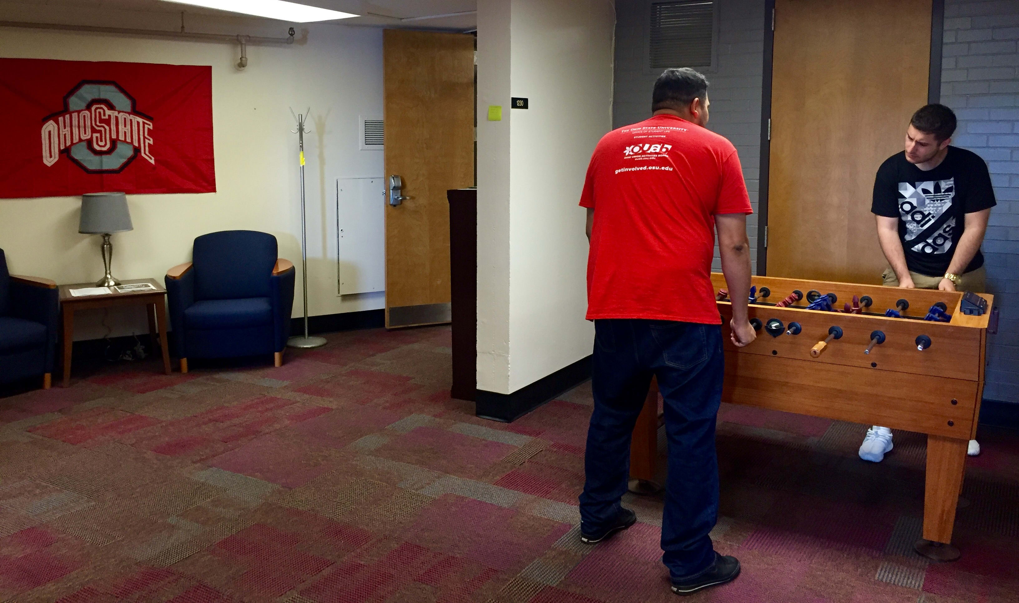 Two students playing foosball in common area