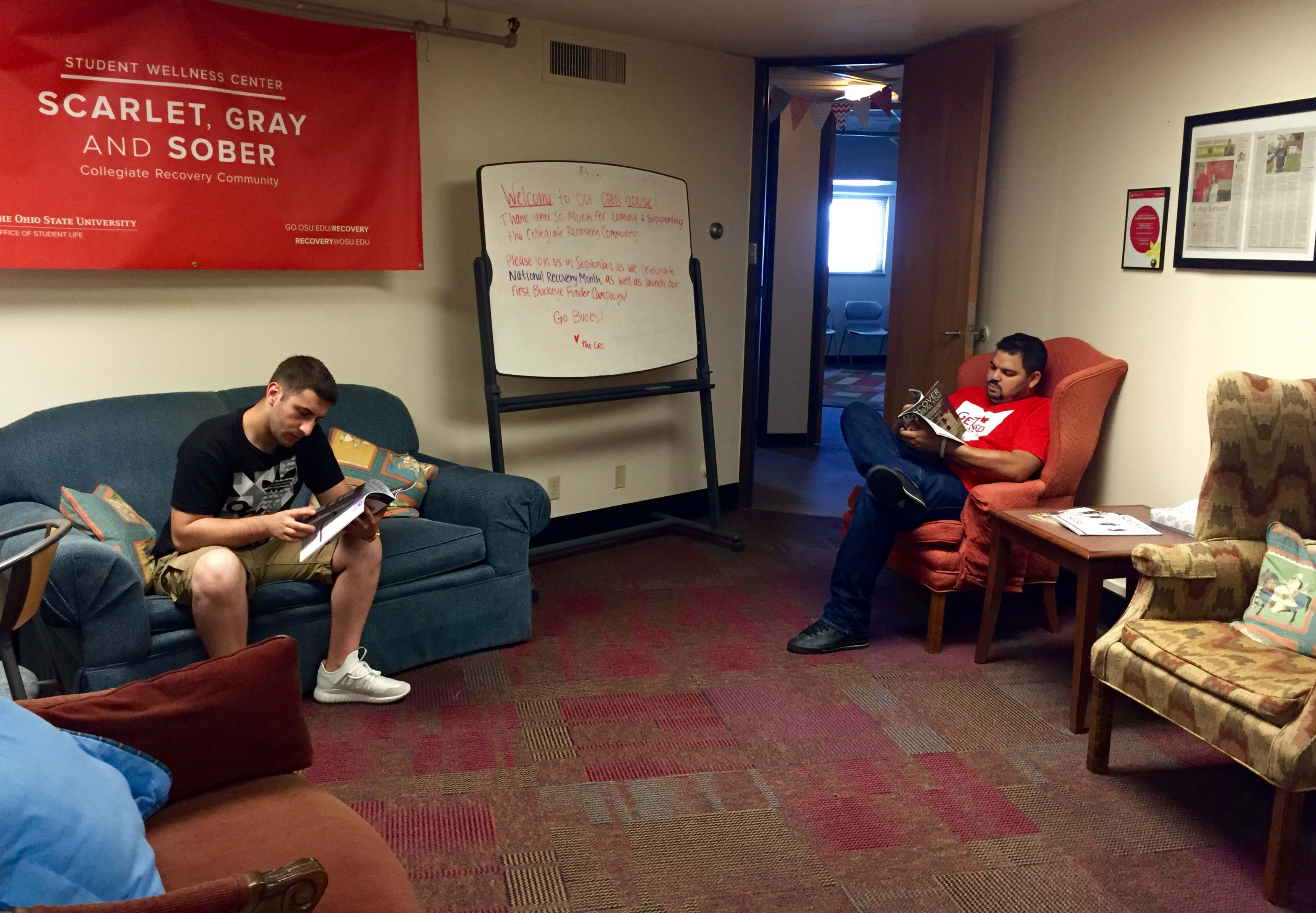Two students sit on different chairs, reading