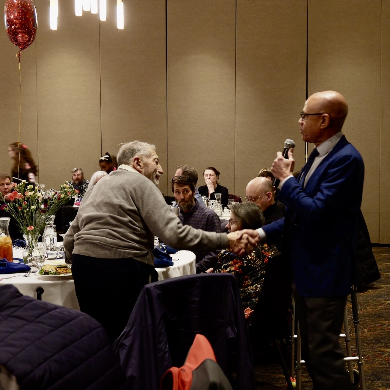 Roger Burggraf shakes hands with a speaker.