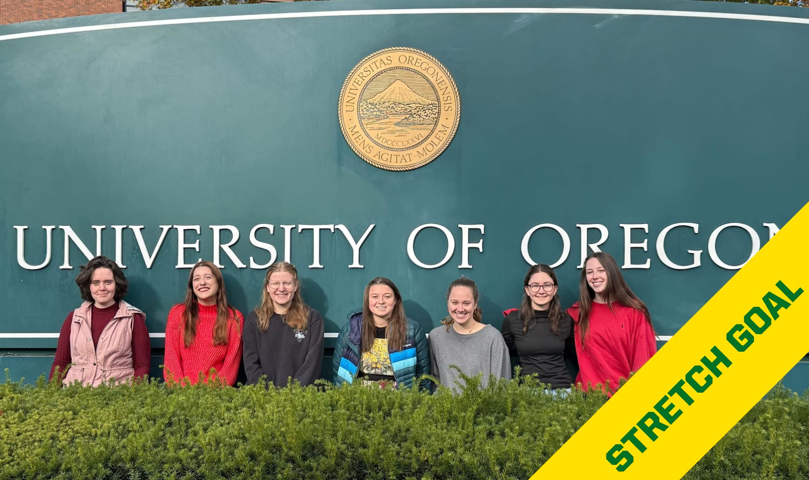 WGS members pose in front of a UO sign