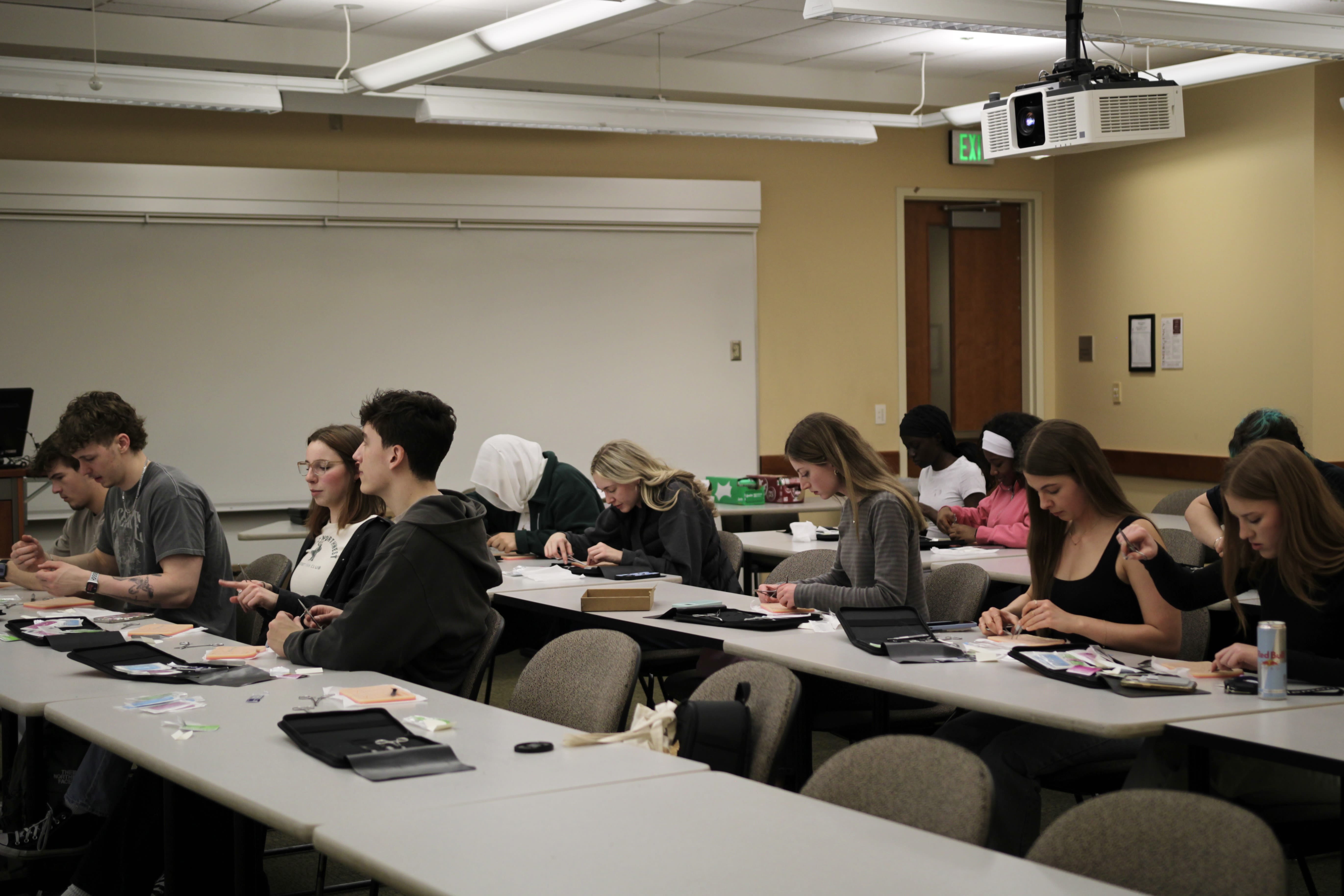 A full classroom of students suturing