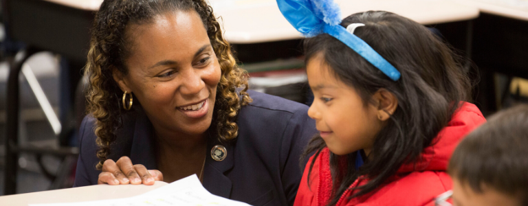 Woman speaking to child helping her with school work