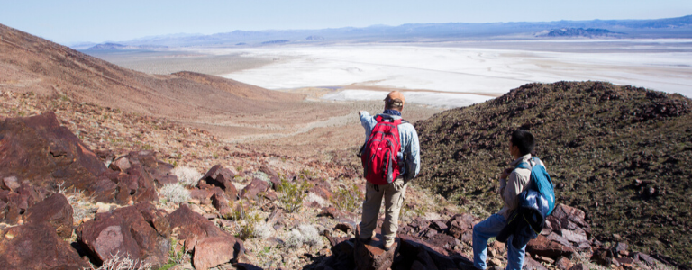 two people standing on mountain looking out at a valley