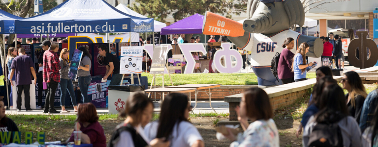 Crowd of people outside with booths and a blow up elephant