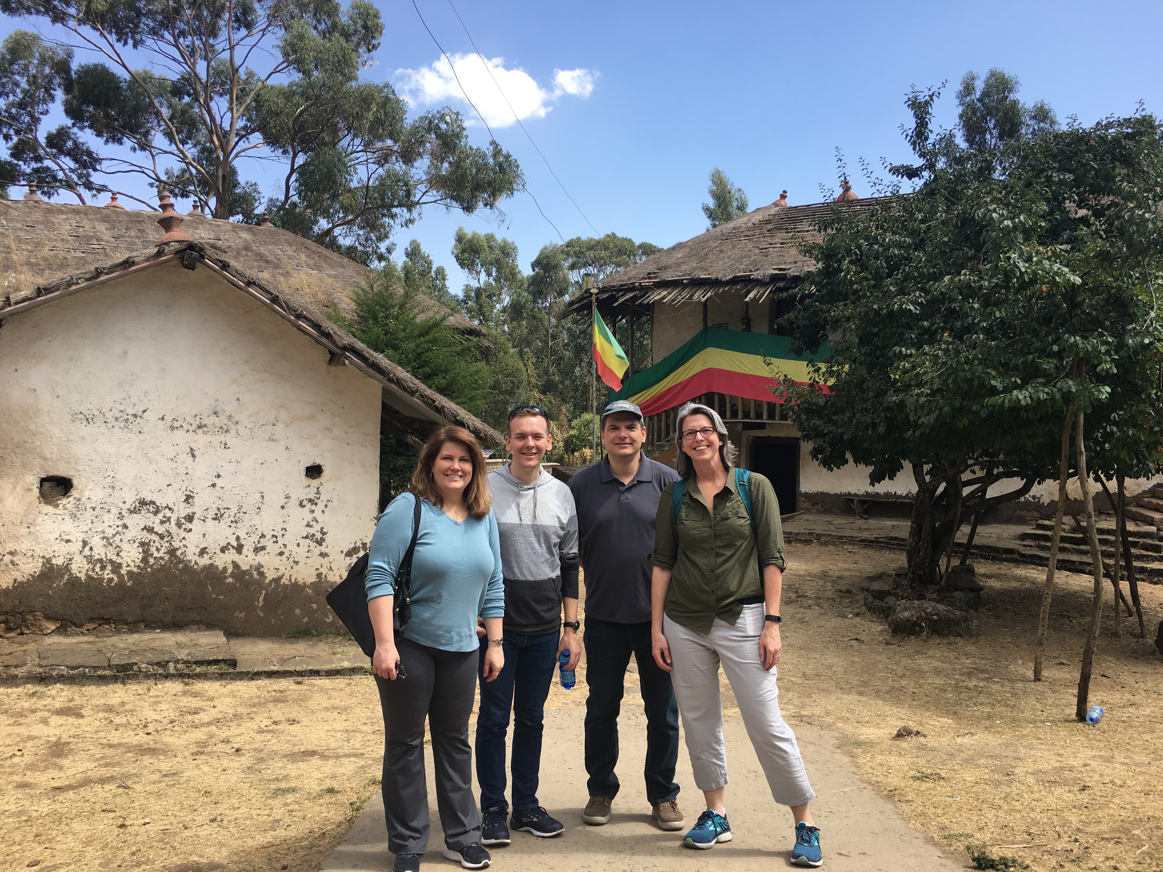 Four individuals standing outside various buildings