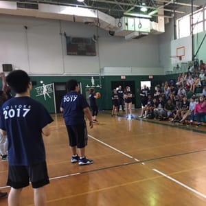 Middle schoolers standing on an indoor basketball court or watching from the stands