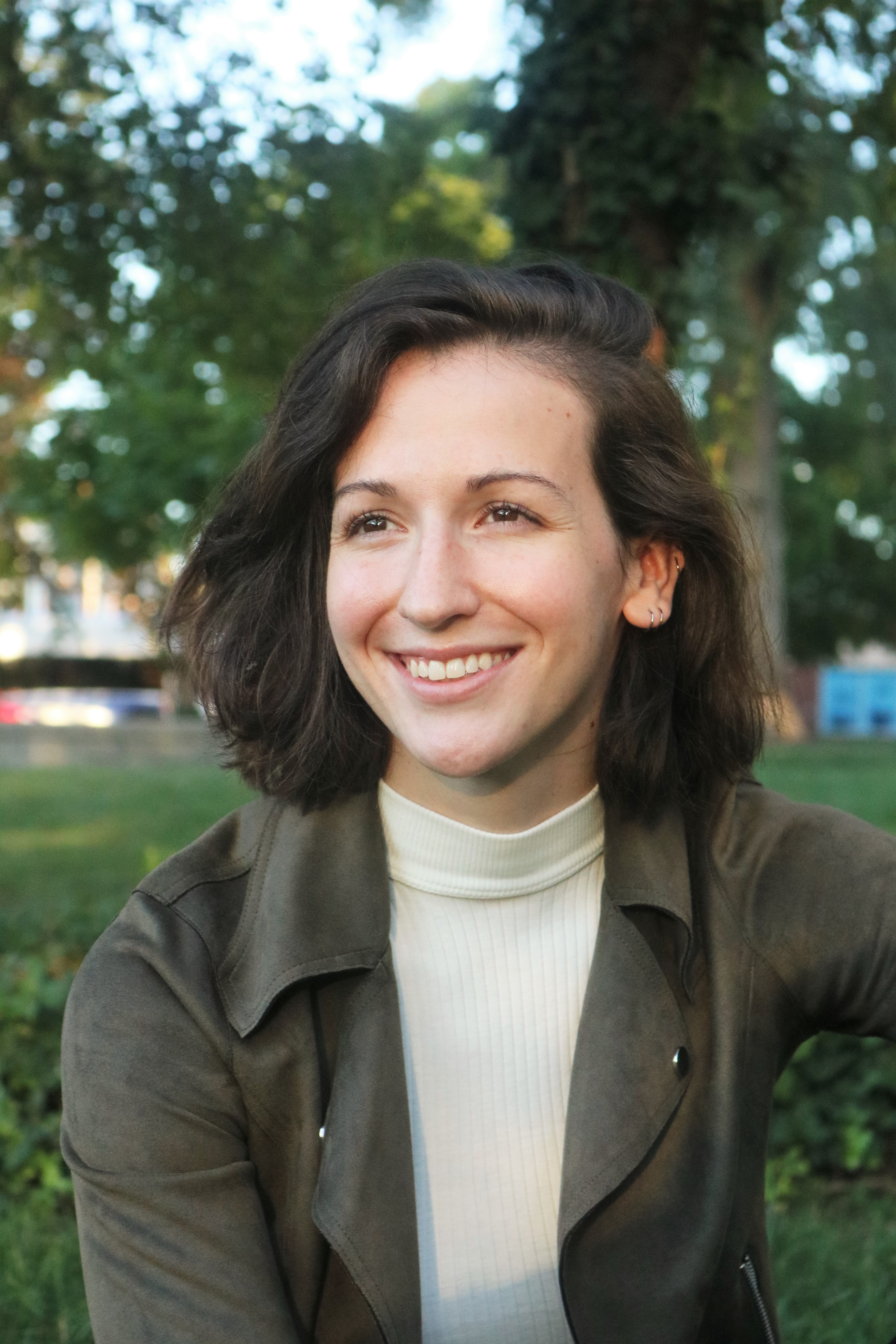 Megan Porter sitting in a grassy patch, staring off beyond the camera 