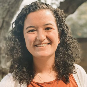 Grace Figliomeni's professional headshot. A large tree stands behind her