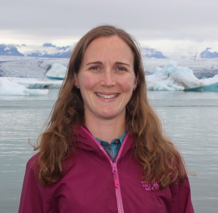 A headshot of Ellyn. She is posed before a patch of water and icebergs.