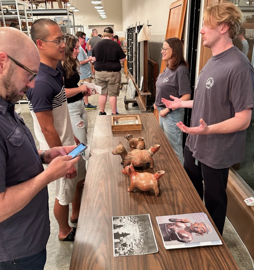 A group of people standing around a table with objects on it

Description automatically generated