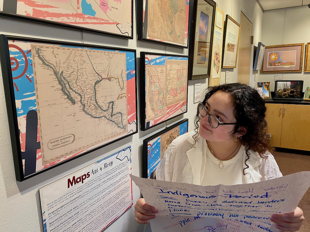 Young woman comparing a chart of observations about maps of Arizona to the maps of Arizona