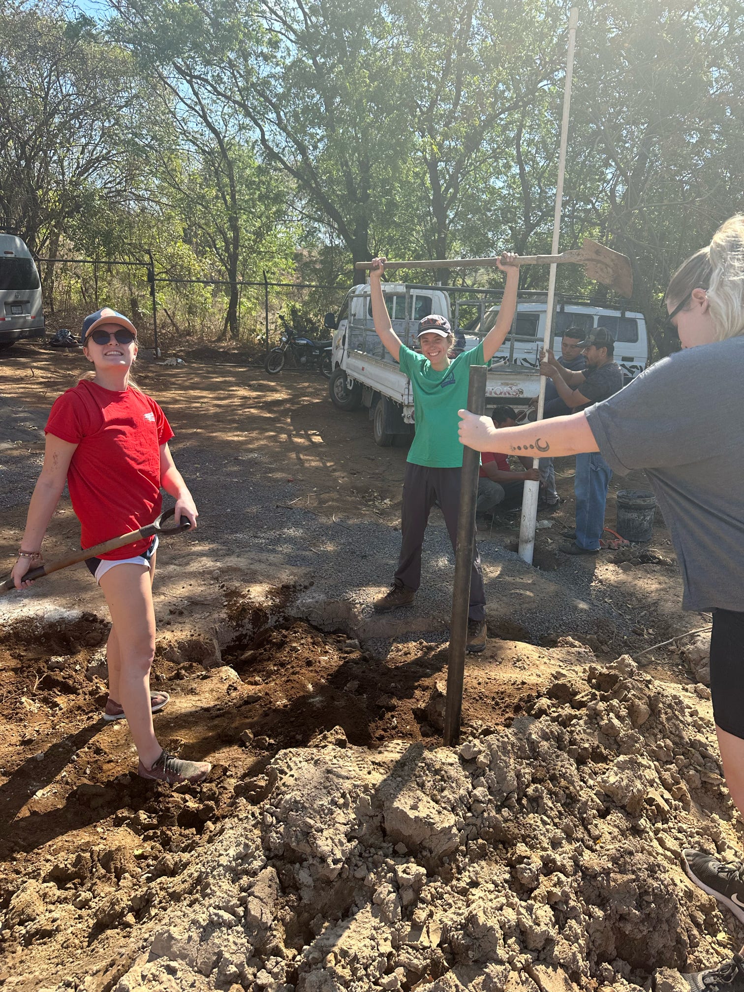 Students working on clearing a patch of dirt. They are carrying shovels 