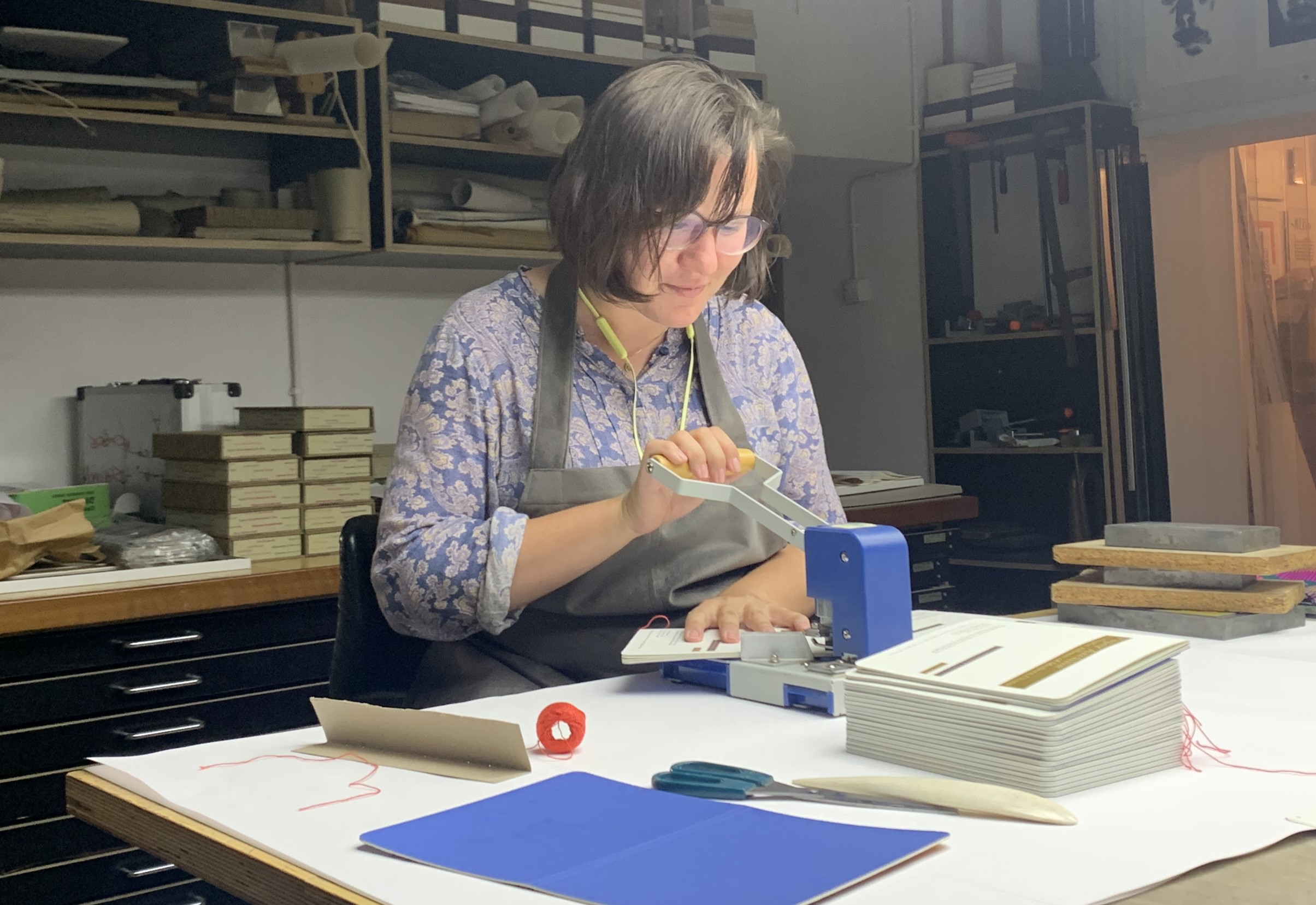 Dr Julia Keblinska working on a machine. She sits at a desk before a stacks of papers 