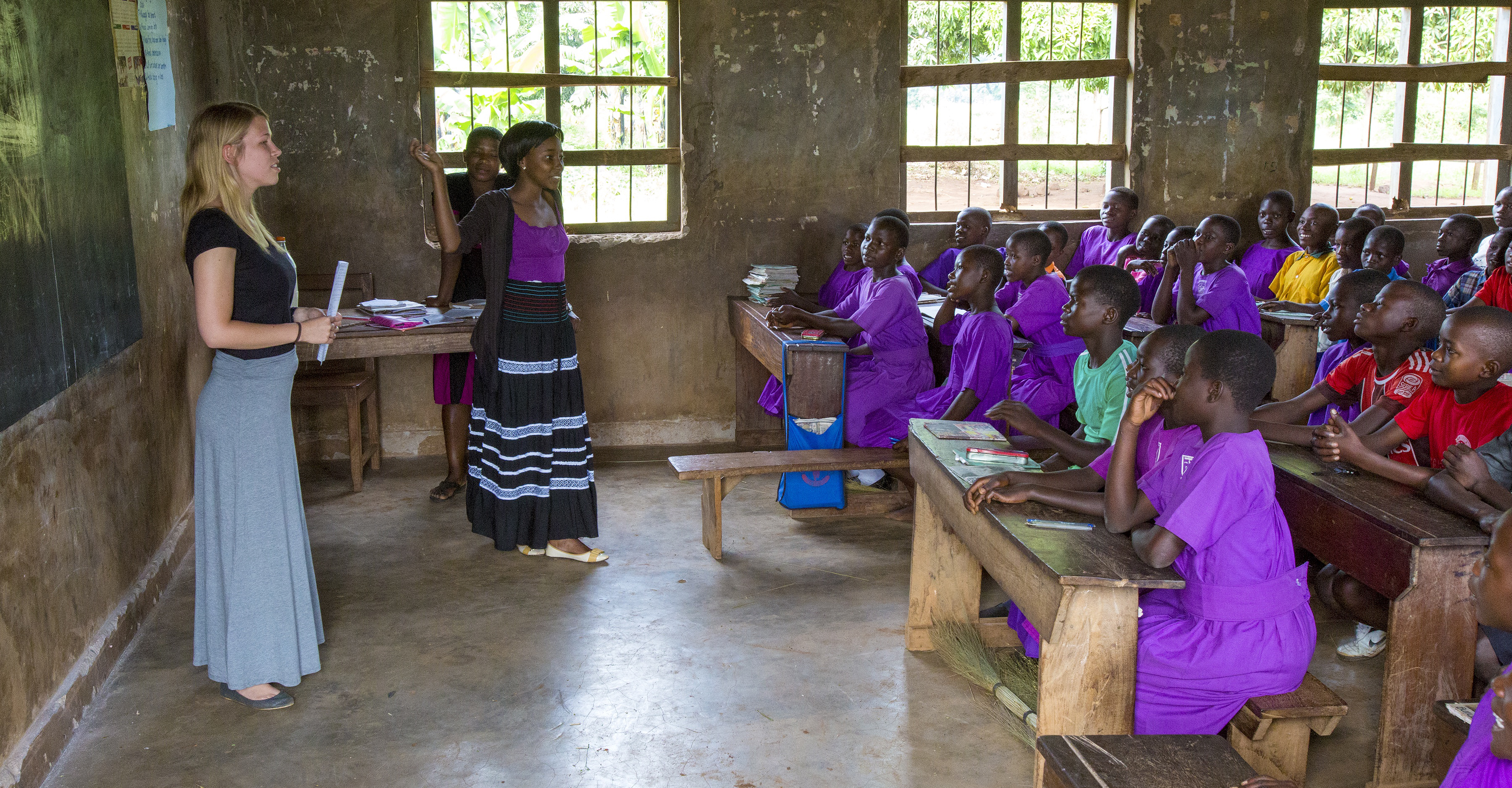 Ugandan children learning in a classroom from two service learning students